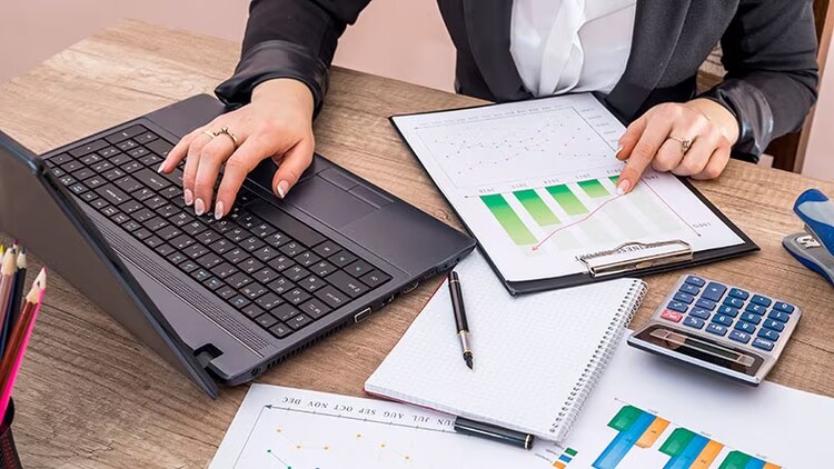 Business continuity management: one hand on laptop keyboard, other hand pointing at printed bar graph