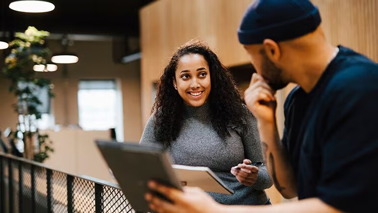 Customer centricity: 2 workers in conversation over a device