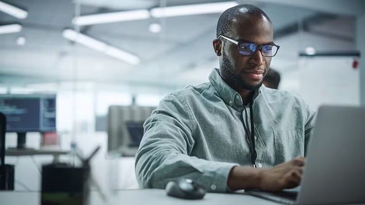 Mitigate cyberthreats with AIOps: man in an office working on a laptop
