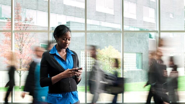 DEI data: Black woman looking at a smartphone while blurred people walk behind her