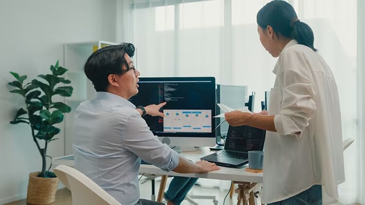 Developer productivity: male developer points to computer monitor while female employee look