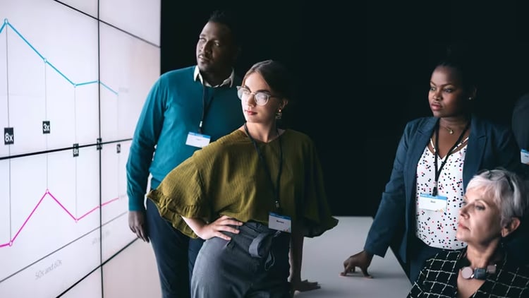 Agility through observability: four workers staring at a graph on a large screen