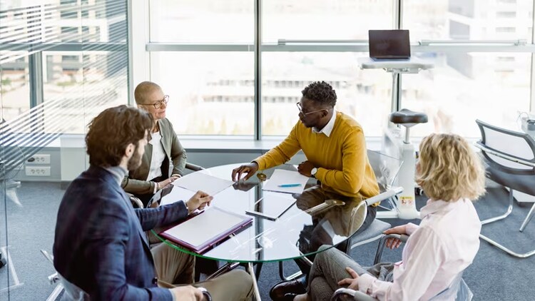 Global regulations: four workers in discussion around a circular table in a high-rise building