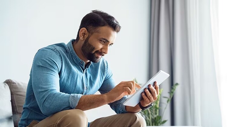 Technology optimization: man sitting on sofa looking at tablet in hands