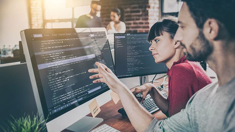 Reduce MTTR: two employees looking at a computer screen in an office