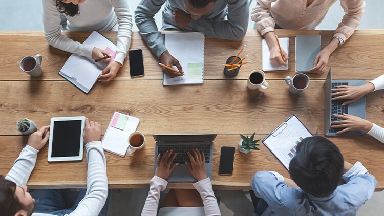 Modernize enterprise resource planning: Top-down view of seven employees working at a conference table