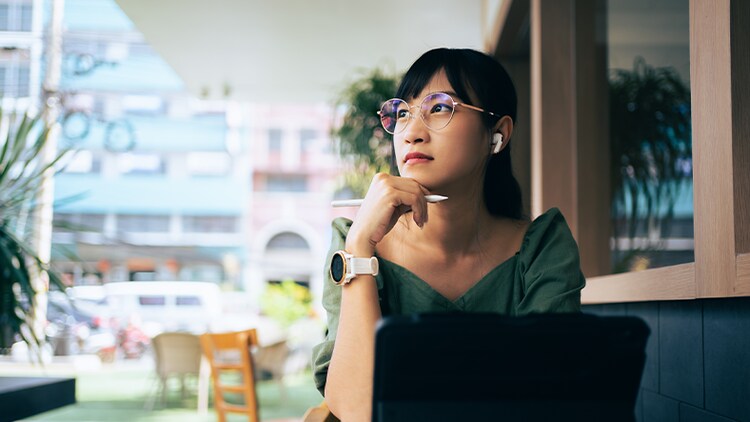 Woman looking off in the distance while working on a tablet