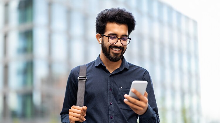 Overcoming customer service challenges: man holding and smiling at phone in front of a tall building