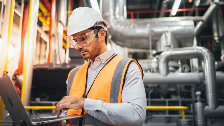 Man using a laptop for manufacturing operations on the factory floor