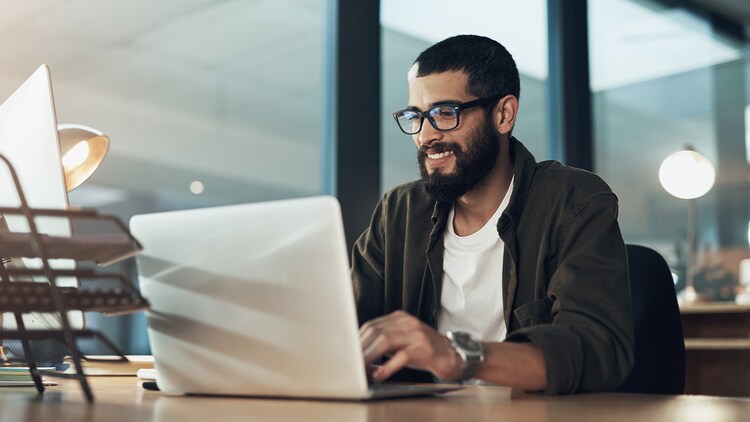 AI asset lifecycle: man sitting at a desk and smiling at an open laptop