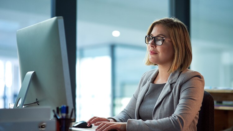 Ethical AI: woman in a windowed office typing on a desktop computer