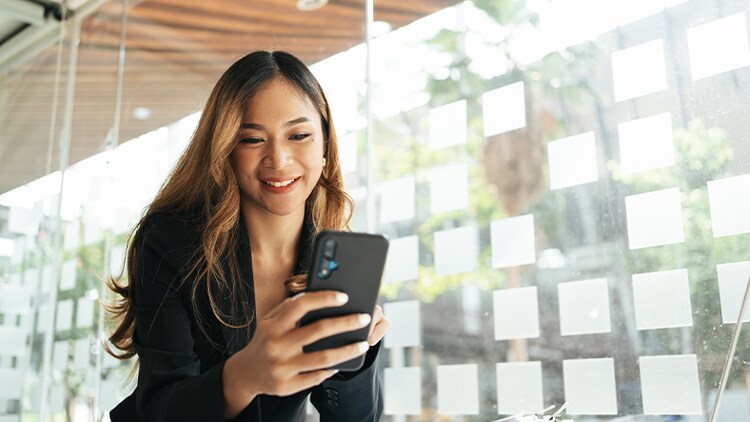 National productivity: woman in an office smiling at the phone in her hand
