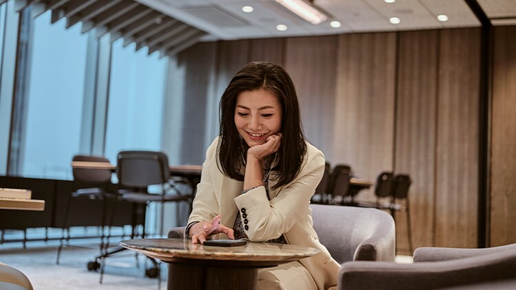 Customer experience insights: woman smiling at her phone on a table in an office