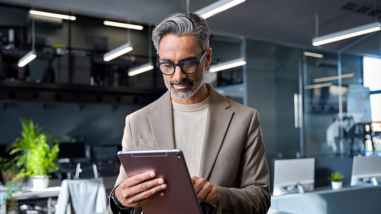 AI platforms: man standing in an office tapping a tablet in his hands