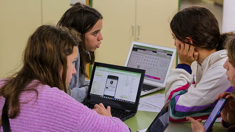 Empower youth: four girls gathered around laptops