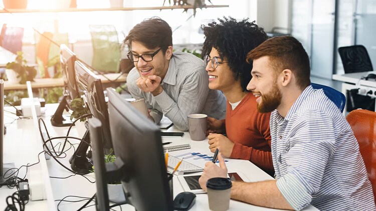 ITAM success: three workers looking at a computer monitor in an office
