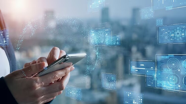 Generative AI in telecom: hands holding a smartphone against a backdrop of computer screen displays