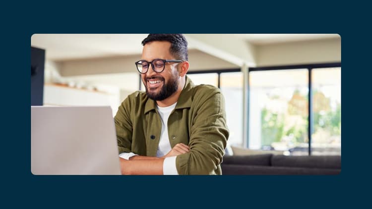 Now Support: man smiling at an open laptop