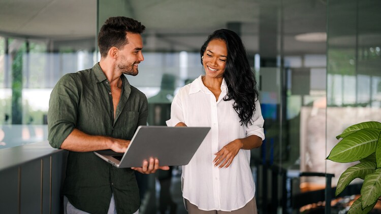 High-risk AI systems: A man and woman standing in an office looking at a laptop