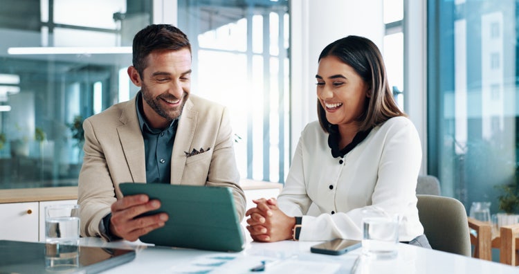 2 happy workers collaborating over a tablet in a bright office