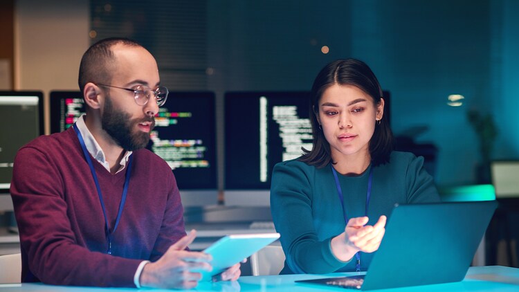 Threat intelligence: two workers looking at a laptop screen in an office