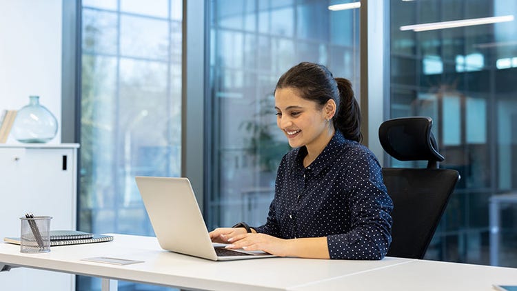 Demographic dividend: woman smiling at open laptop in an office