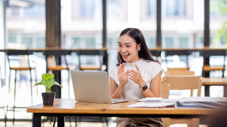 Closing the service gap in Singapore: woman smiling and clapping at open laptop in a modern office
