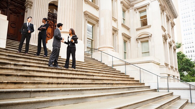 Government efficiency: four employees standing on the steps outside a government building