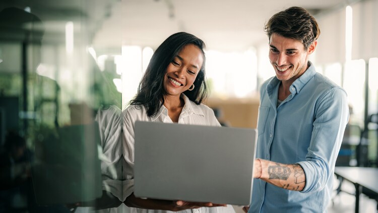 AI in action: two co-workers smiling at a laptop in an office setting