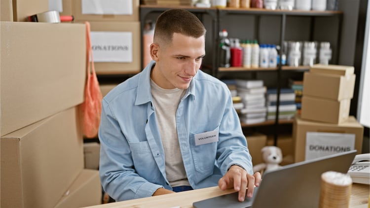 AI for nonprofits: volunteer in a stockroom smiling at an open laptop