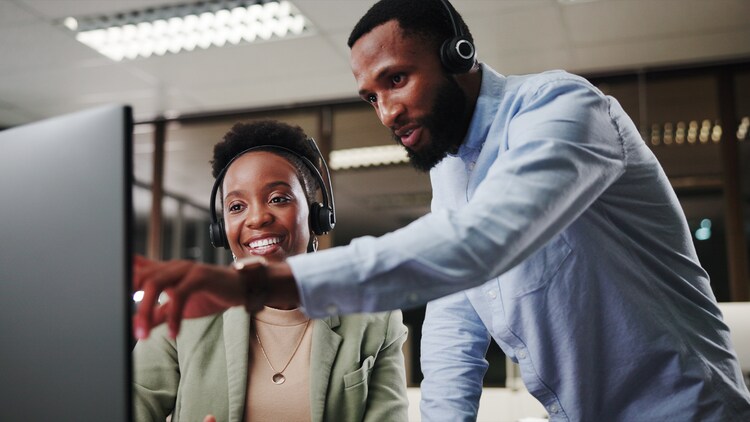 Reinventing CRM: two customer service workers looking at a computer monitor