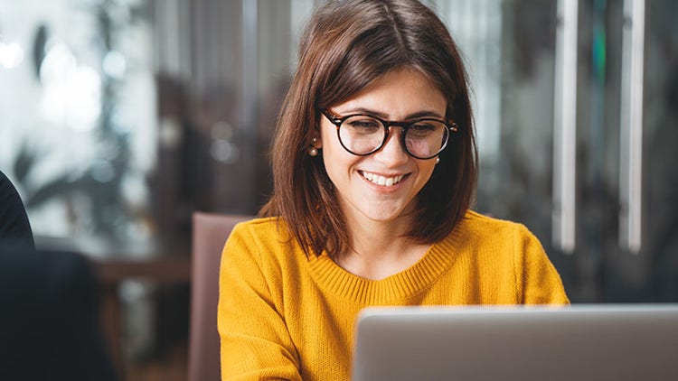 AI potential: smiling worker looking at her open laptop