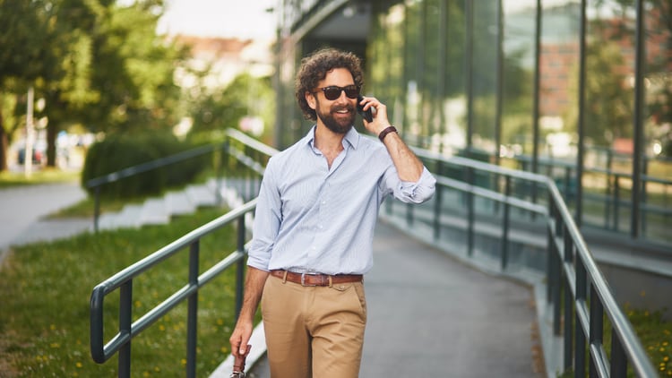 Telecom CX: walking man smiling while talking on the phone outdoors