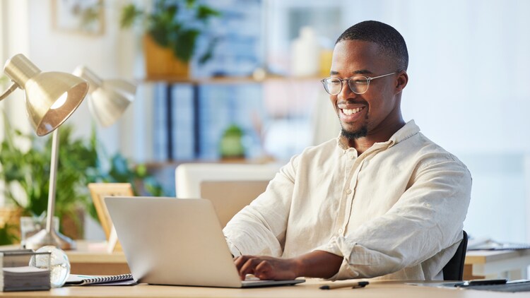 Confident man typing on a laptop in a bright office
