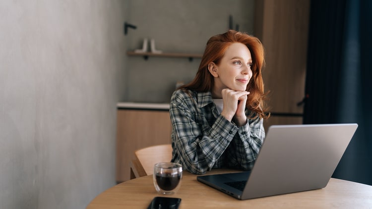 Autonomous IT: woman looking to the side in front of an open laptop on a table