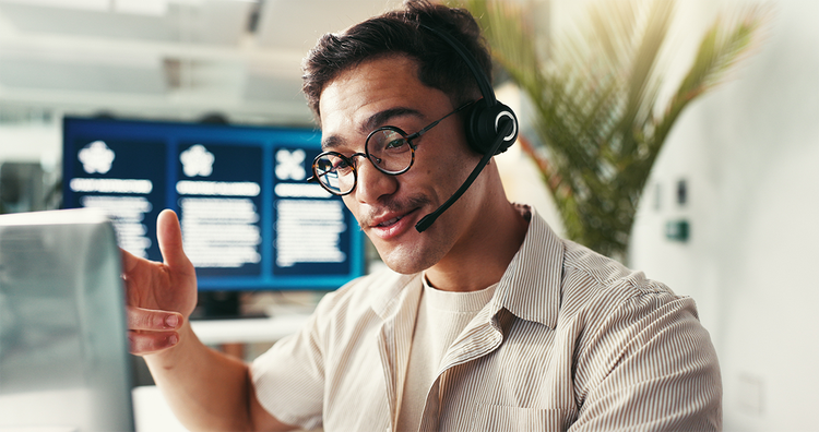 Man wearing a headset talking to a customer while looking at his computer monitor