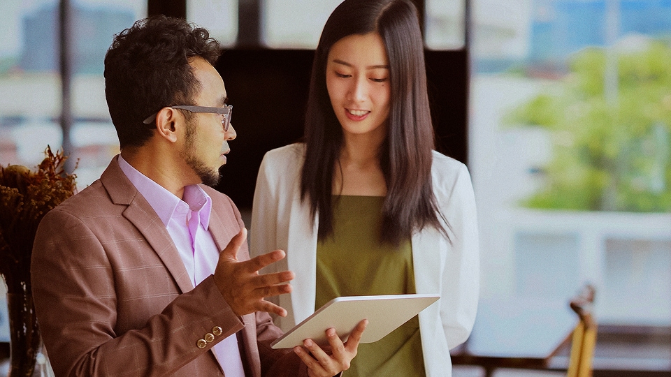 Coworkers discussing an app displayed on a mobile device.