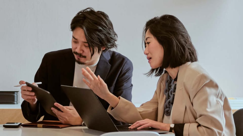 Een vrouw en een man die op kantoor op hun laptops werken
