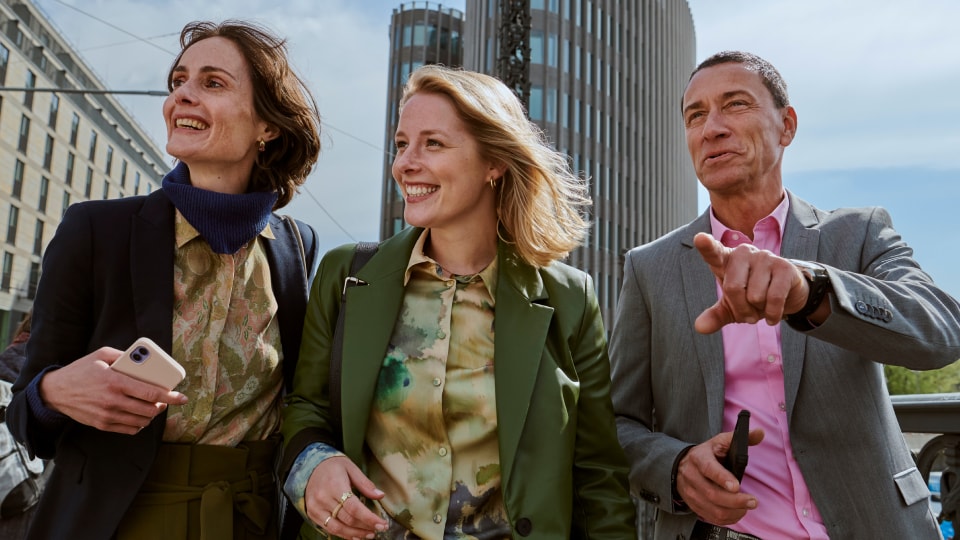 Twee vrouwen en een man lopen langs een straat