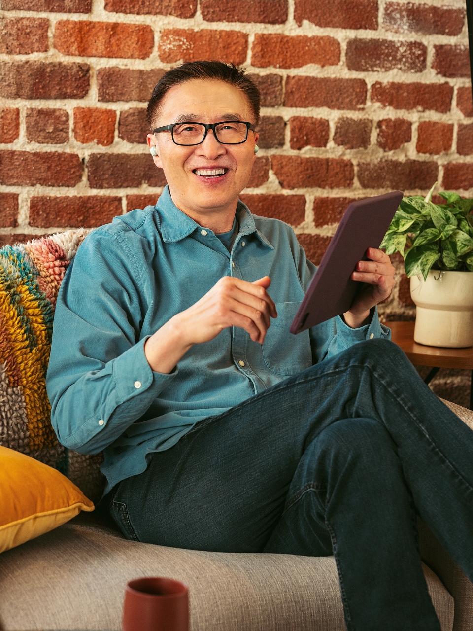 Un apprenant se détend sur un canapé avec une tablette et suit un parcours de formation personnalisé ServiceNow University.