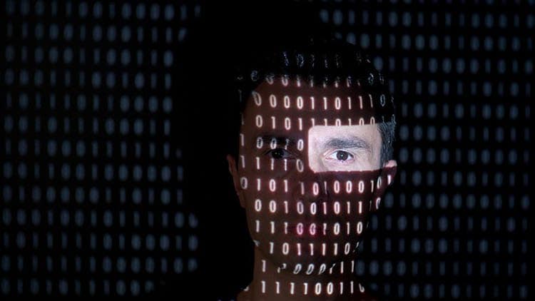 Ransomware-Abwehr: Man sieht das linke Auge eines Mannes, der Rest seines Gesichts ist mit Binär-Code bedeckt.