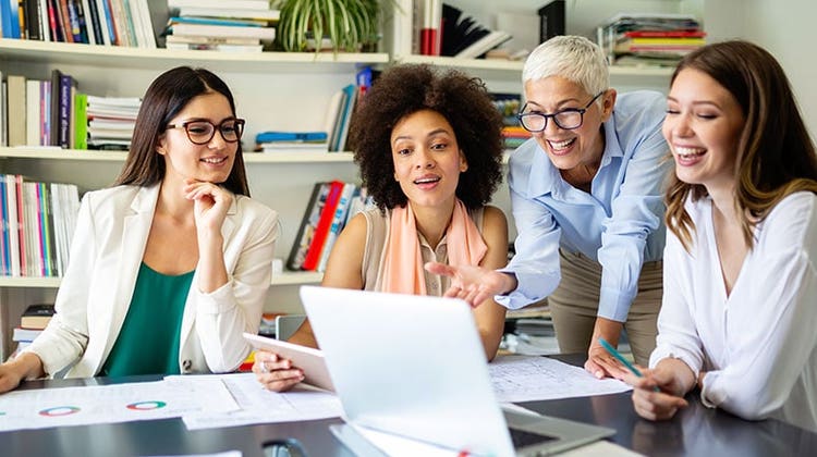 Diversität als schlüssel zum erfolg: Vier Frauen schauen auf einen Laptop