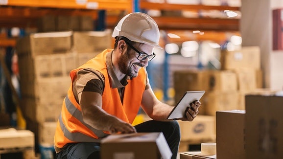 Logistikmitarbeiter arbeitet mit Tablet im Lager