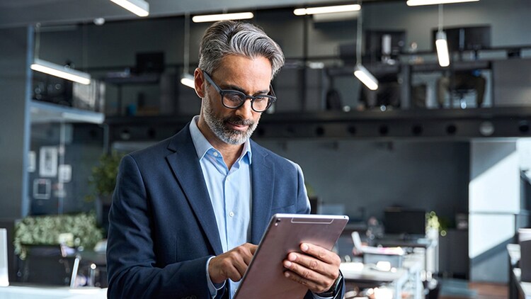 Führungskraft, die in einem modernen Büroumfeld auf einem Tablet Dashboard-Daten prüft