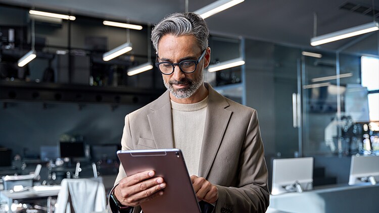 Plateformes d’IA : homme debout dans un bureau tapant sur une tablette entre ses mains