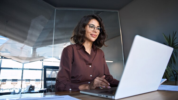 Rôle de l’IT : femme travaillant sur un ordinateur portable dans un bureau moderne