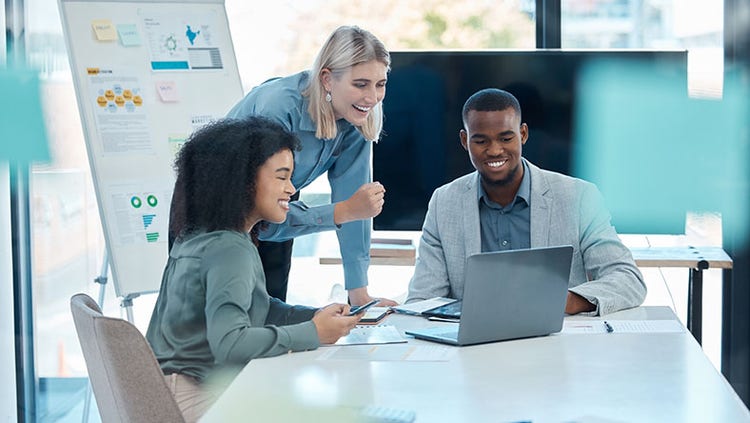 Trois personnes souriant ensemble devant un écran d'ordinateur