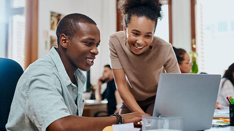Implication des employés : deux employés de bureau souriant devant un ordinateur portable ouvert