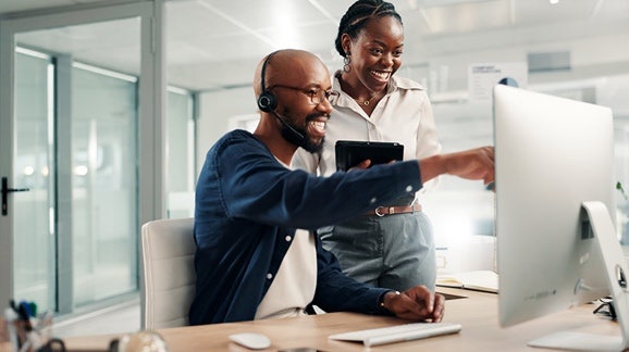 IA et relation client : équipe de centre d'appels aidant un client sur ordinateur.