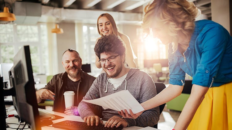 Équipe diverse de Global Business Services collaborant autour d'un ordinateur portable